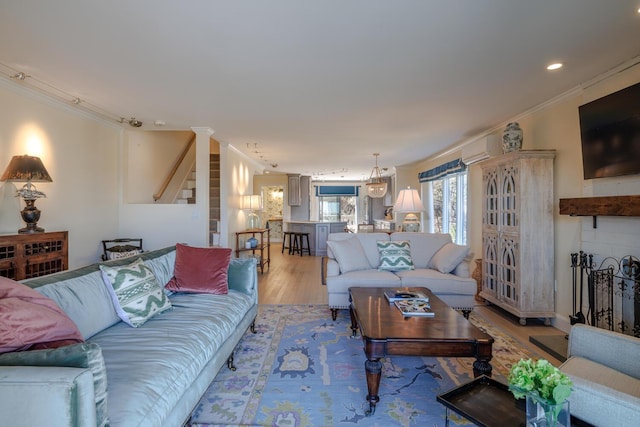 living room featuring light wood-style flooring, crown molding, stairs, a chandelier, and recessed lighting
