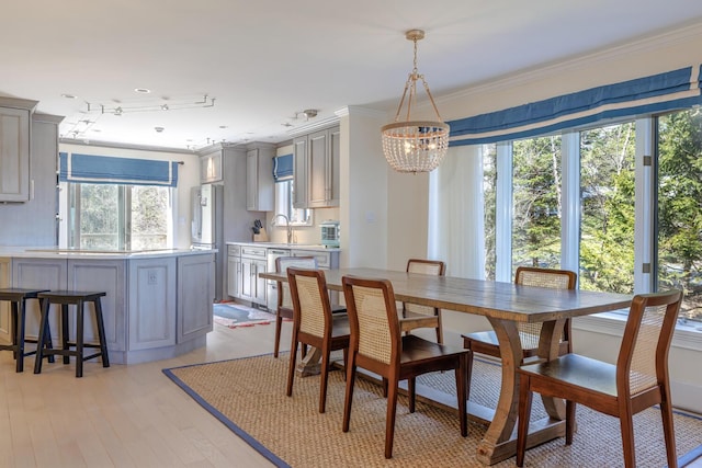 dining space featuring crown molding, a chandelier, and light wood-style flooring