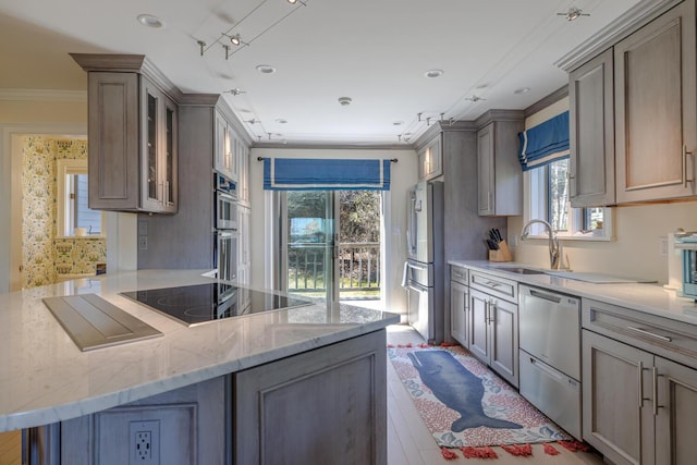 kitchen featuring a sink, stainless steel appliances, crown molding, a peninsula, and light stone countertops
