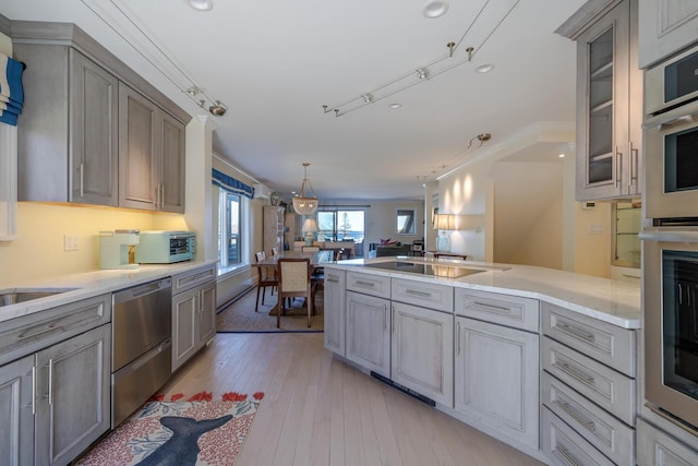 kitchen with appliances with stainless steel finishes, gray cabinets, open floor plan, glass insert cabinets, and recessed lighting