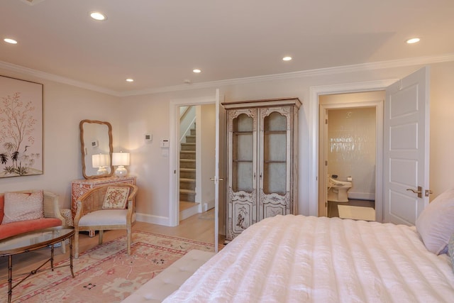 bedroom featuring baseboards, recessed lighting, crown molding, light wood-style flooring, and connected bathroom