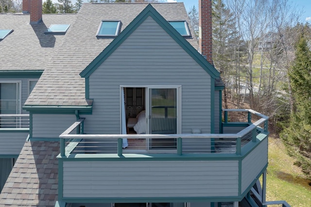 view of home's exterior featuring roof with shingles, a chimney, and a balcony