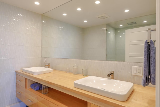bathroom with tile walls, recessed lighting, tasteful backsplash, and double vanity