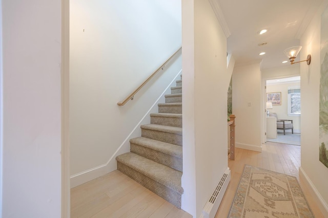 staircase with a baseboard radiator, ornamental molding, hardwood / wood-style flooring, recessed lighting, and baseboards