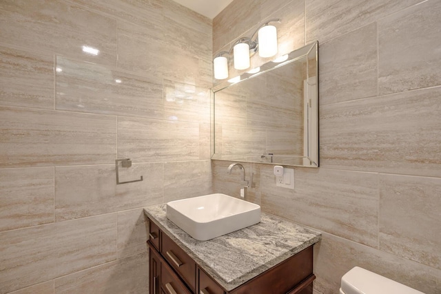 half bath featuring tile walls, vanity, toilet, and tasteful backsplash