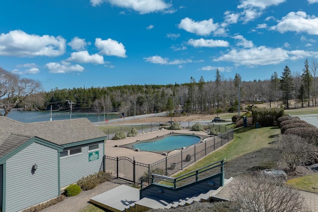 view of pool with a wooded view and fence