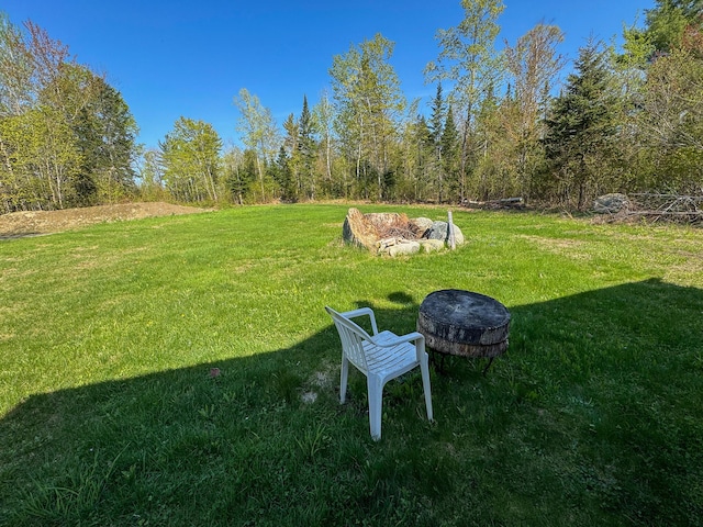 view of grassy yard featuring an outdoor fire pit
