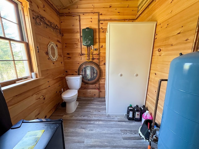 bathroom featuring wood walls, wood finished floors, lofted ceiling, and toilet