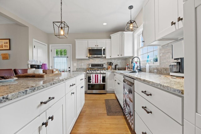 107 Elm St, South Portland, ME 04106 - kitchen featuring stainless steel appliances, a sink, tasteful backsplash, white cabinetry, and light wood-type flooring