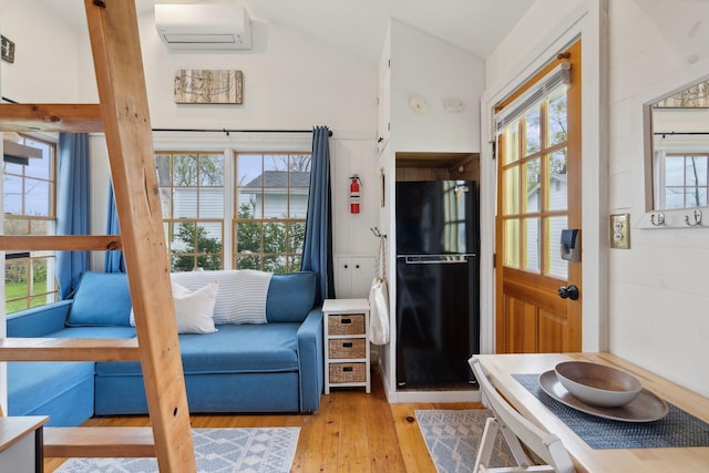 living room featuring an AC wall unit, wood finished floors, and vaulted ceiling
