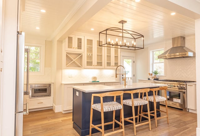 104 Woodbridge Rd, York, ME 03909 - kitchen featuring wall chimney range hood, stainless steel appliances, a sink, decorative backsplash, and light wood-style flooring