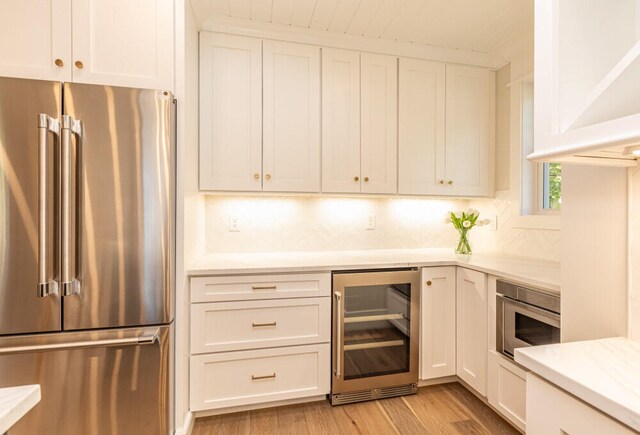 104 Woodbridge Rd, York, ME 03909 - kitchen with high end fridge, wine cooler, white cabinets, light wood-type flooring, and light stone counters