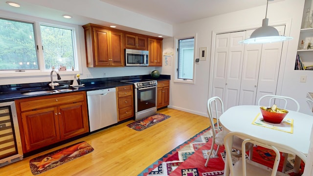 28 Meadow Ln, Brewer, ME 04412 - kitchen with stainless steel appliances, beverage cooler, a sink, dark countertops, and light wood-style floors
