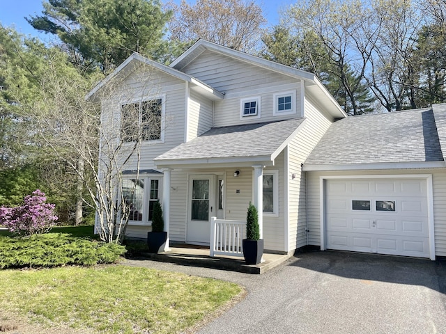 traditional-style home with a garage, roof with shingles, and asphalt driveway