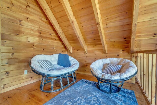 sitting room with beamed ceiling, wood finished floors, wood ceiling, and wood walls