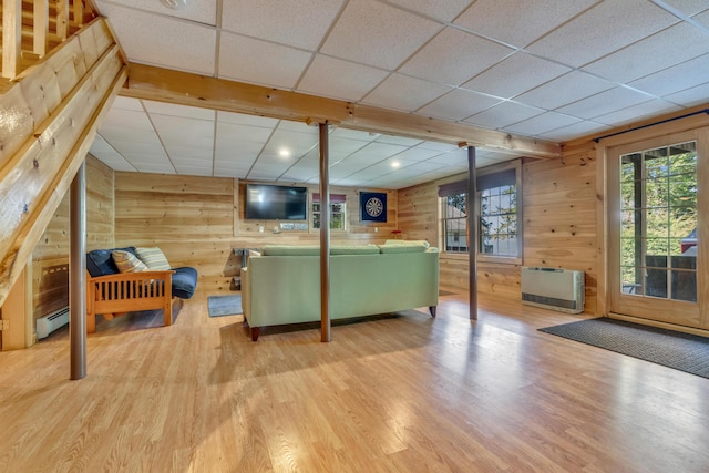 living room featuring wooden walls, a paneled ceiling, wood finished floors, baseboard heating, and heating unit