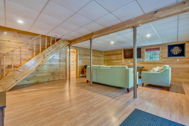 living room featuring wood finished floors, wood walls, and a drop ceiling