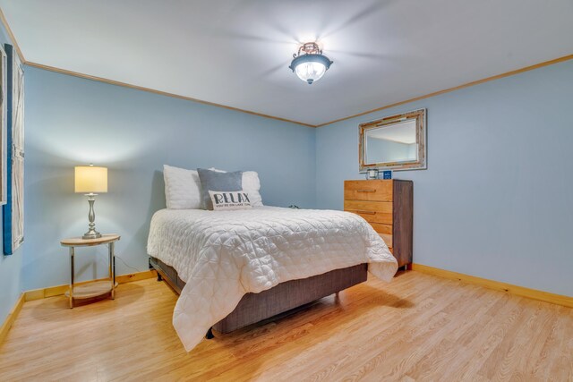 bedroom featuring baseboards, wood finished floors, and crown molding