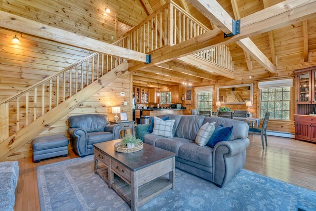 living room featuring wood walls, hardwood / wood-style floors, healthy amount of natural light, stairs, and beam ceiling