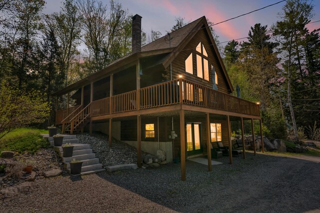 rear view of house with a chimney, a wooden deck, and stairway