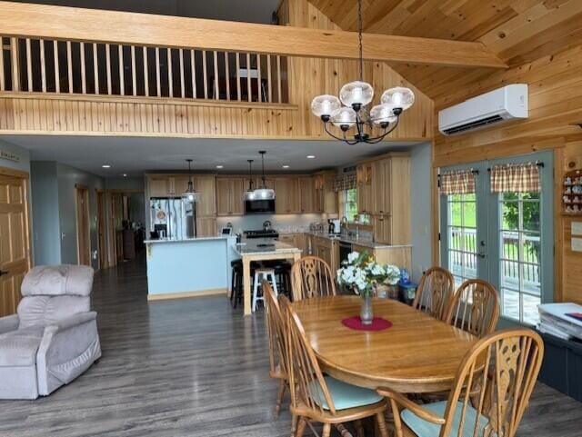 1027 Gardner Creek Rd, Wade, ME 04786 - dining space featuring a wall mounted AC, a chandelier, wood finished floors, beamed ceiling, and wood walls