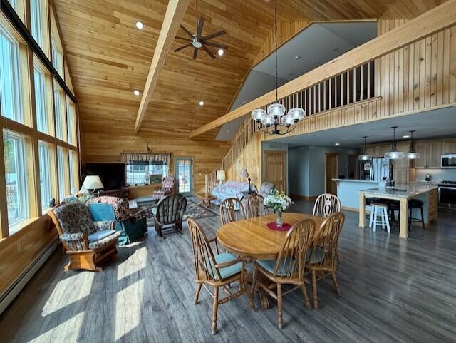 1027 Gardner Creek Rd, Wade, ME 04786 - dining room featuring high vaulted ceiling, a baseboard radiator, wood finished floors, a chandelier, and wooden walls