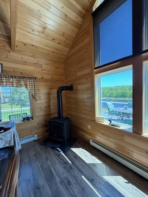 1027 Gardner Creek Rd, Wade, ME 04786 - interior space featuring a baseboard heating unit, wood walls, wood ceiling, wood finished floors, and a wood stove
