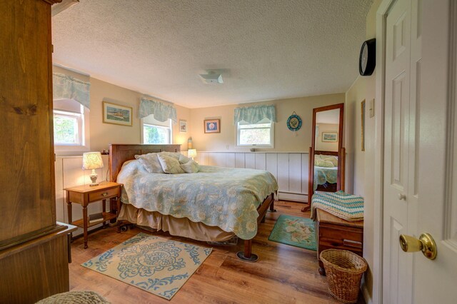74 Spear Rd, Standish, ME 04084 - bedroom featuring multiple windows, a baseboard heating unit, a textured ceiling, a wainscoted wall, and wood finished floors