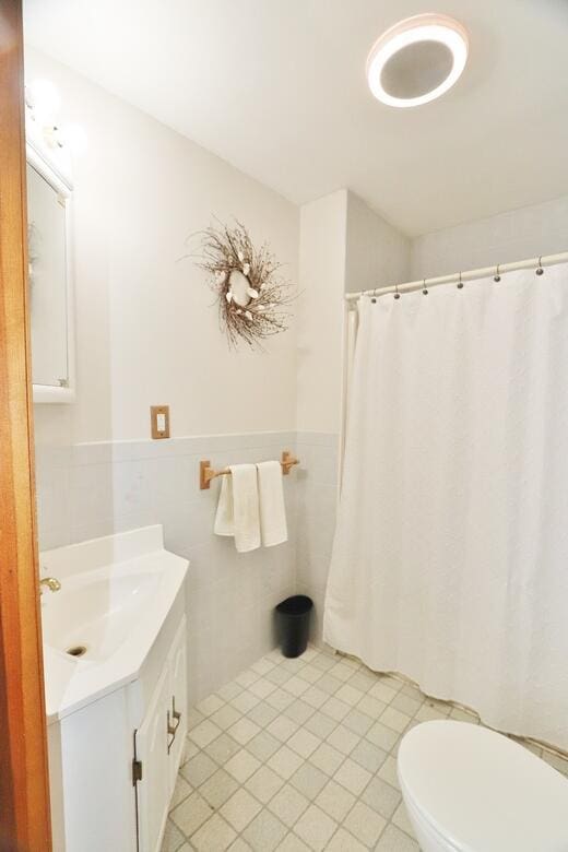 387 Nicolin Rd, Ellsworth, ME 04605 - full bathroom with vanity, toilet, tile patterned flooring, tile walls, and a wainscoted wall