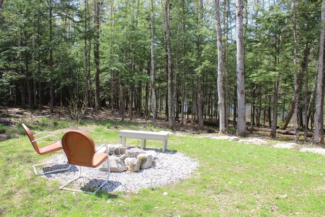 382 Riverbend Rd, Brownfield, ME 04010 - view of green lawn featuring a fire pit and a wooded view