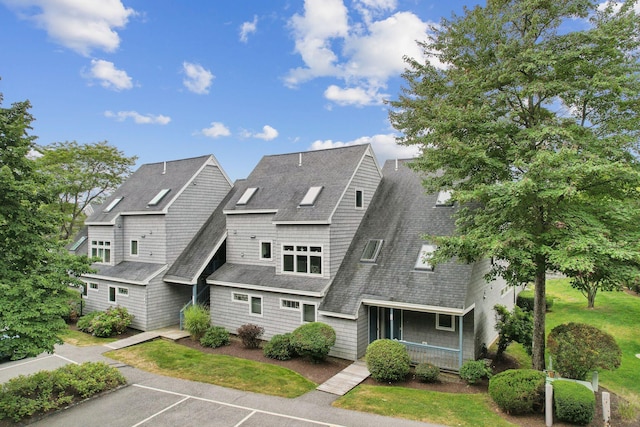 view of front facade with a shingled roof, uncovered parking, and covered porch