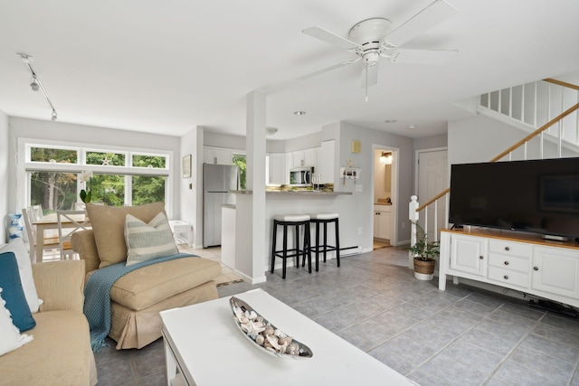 living room featuring stairs, ceiling fan, light tile patterned flooring, baseboards, and track lighting