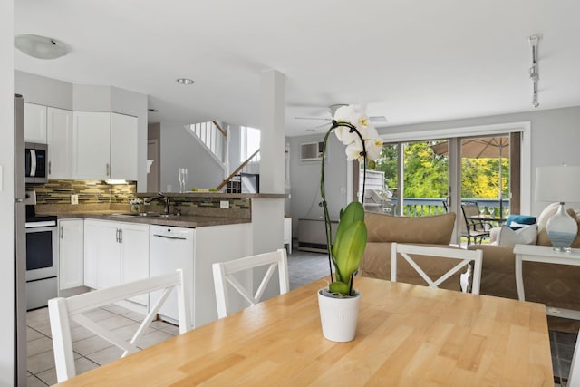 dining space featuring light tile patterned floors, ceiling fan, stairs, a wall unit AC, and rail lighting