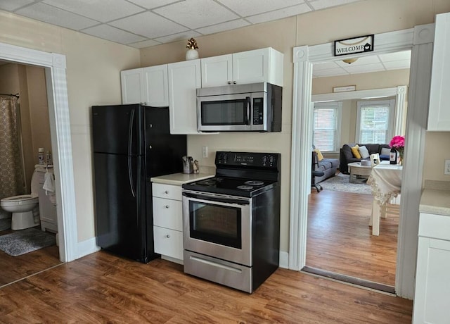 20 Sylvan Ave, Lewiston, ME 04240 - kitchen with stainless steel appliances, white cabinetry, wood finished floors, light countertops, and a paneled ceiling