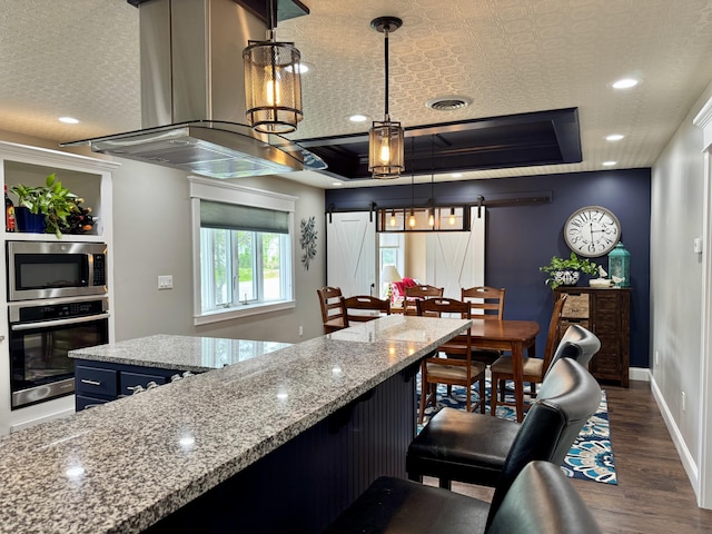 10 Goulet St, Lewiston, ME 04240 - kitchen with appliances with stainless steel finishes, dark wood finished floors, exhaust hood, a kitchen breakfast bar, and light stone countertops