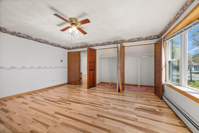 164 Dewitt Ave, Bangor, ME 04401 - unfurnished bedroom featuring a baseboard heating unit, two closets, light wood-style floors, baseboards, and ceiling fan