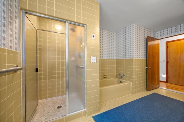 164 Dewitt Ave, Bangor, ME 04401 - bathroom with wallpapered walls, tile walls, a shower stall, a bath, and wainscoting