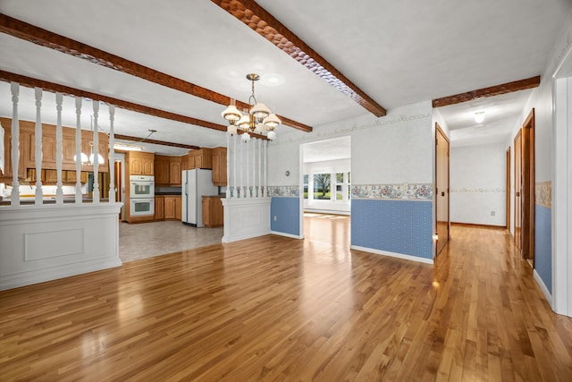 164 Dewitt Ave, Bangor, ME 04401 - unfurnished living room with a chandelier, beamed ceiling, light wood-type flooring, wallpapered walls, and a wainscoted wall