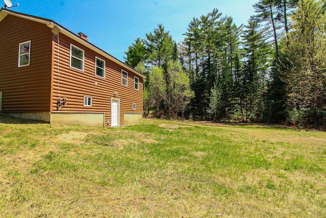342 Spring Bridge Rd, Greenbush, ME 04418 - view of home's exterior with a yard, faux log siding, and a chimney