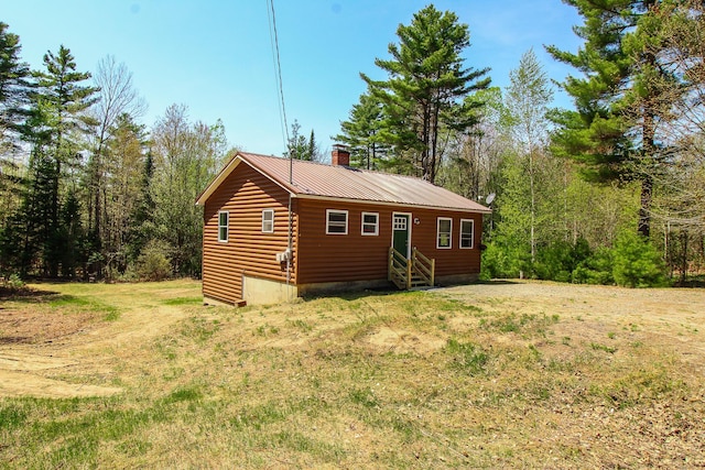 342 Spring Bridge Rd, Greenbush, ME 04418 - view of front of house with entry steps, faux log siding, a chimney, metal roof, and a front lawn