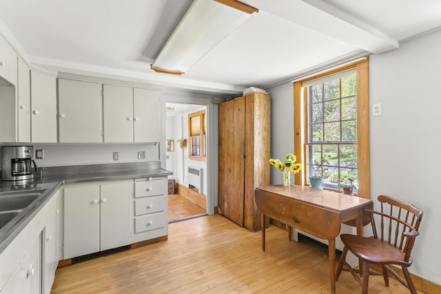 42 Winthrop St, Hallowell, ME 04347 - kitchen featuring stainless steel counters, radiator, light wood-type flooring, and white cabinetry