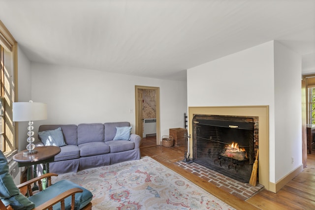 42 Winthrop St, Hallowell, ME 04347 - living room with wood-type flooring, radiator heating unit, a lit fireplace, and baseboards