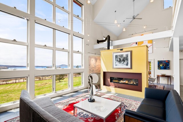 39 Kendall Farm Trl, Rangeley, ME 04970 - living area with high vaulted ceiling, a glass covered fireplace, and ceiling fan