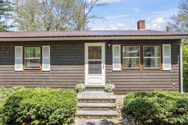 ranch-style home with a chimney and metal roof