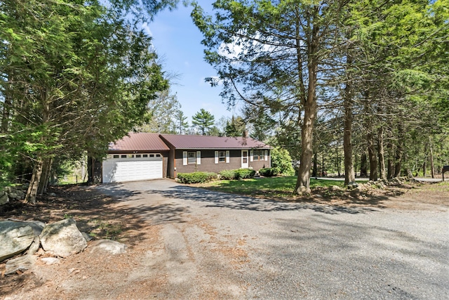 ranch-style home featuring dirt driveway, an attached garage, and metal roof