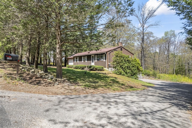 view of front of property featuring a chimney, asphalt driveway, and a front lawn