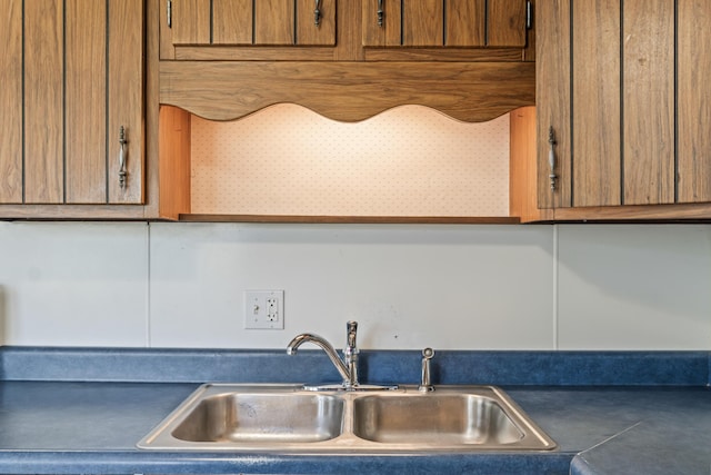 kitchen view of a sink, brown cabinets, and dark countertops
