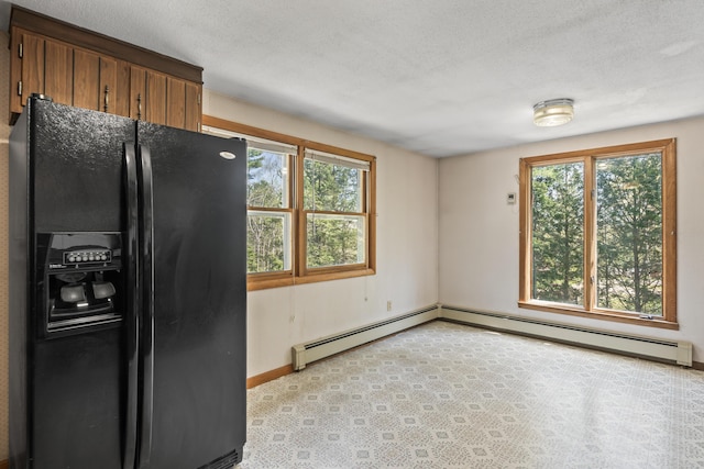 kitchen with black fridge, plenty of natural light, baseboards, and baseboard heating