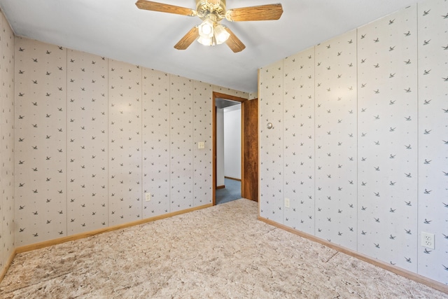 carpeted spare room featuring a ceiling fan and baseboards