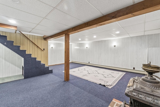 finished below grade area with carpet flooring, stairs, a drop ceiling, recessed lighting, and wooden walls